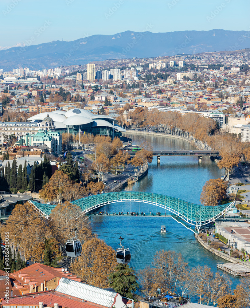 Scenic winter panorama of Tbilisi, Georgia, showcasing the Kura River, the iconic Bridge of Peace, and the unique architecture of the Public Service Hall.