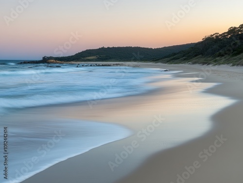 Serene beach at sunset with gentle waves and soft sand.