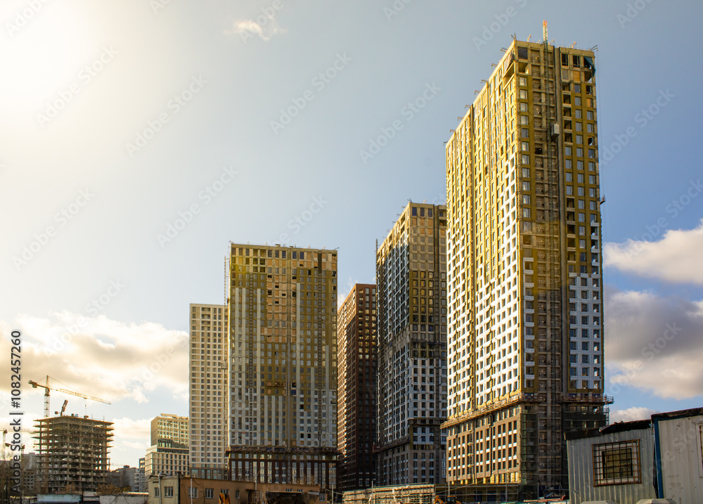 Modern residential complexes under construction. Finishing and insulation of house facades, installation of windows. Construction site. Buildings under construction in the rays of the sun Modern residential complexes under construction. Finishing and insulation of house facades, installation of windows. Construction site. Buildings under construction in the rays of the sun