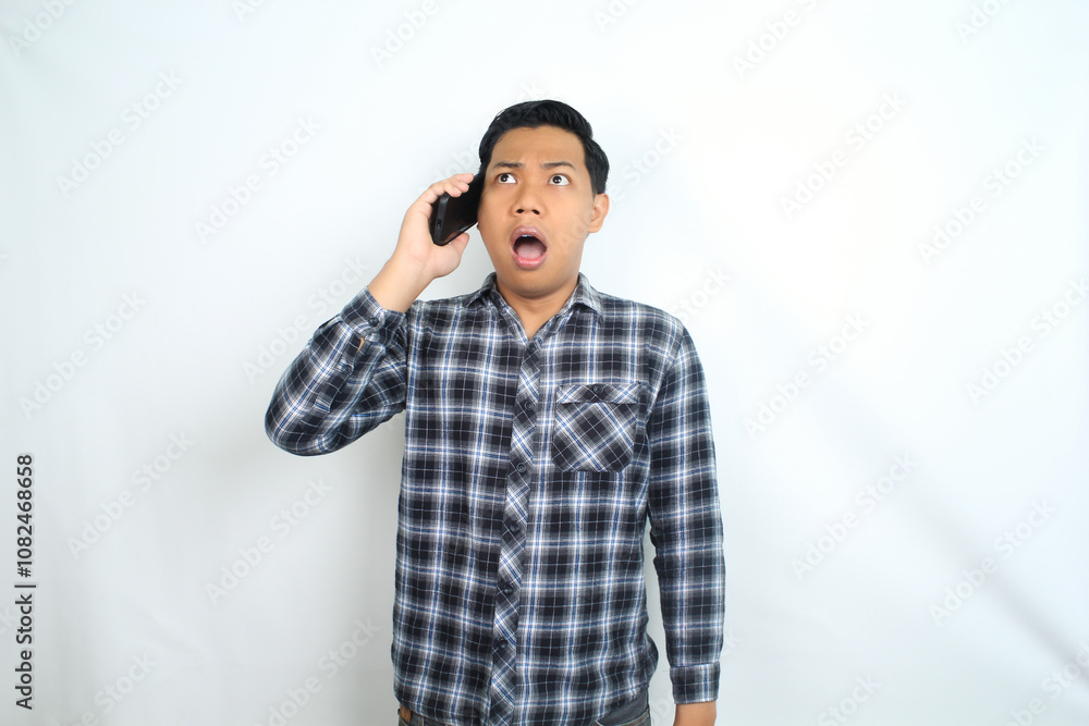 asian man shocked while talking on smartphone, scared and panic expression, isolated on white wearing casual shirt asian man shocked while talking on smartphone, scared and panic expression, isolated on white wearing casual shirt