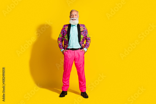 Full body photo of positive smiling old man showman put hands pockets costume isolated yellow color background photo