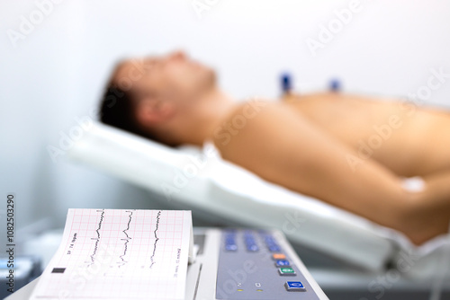 Cardiology examination of patient's heart rhythm. Electrocardiography diagnostic procedure. Electrocardiogram printed on paper. photo