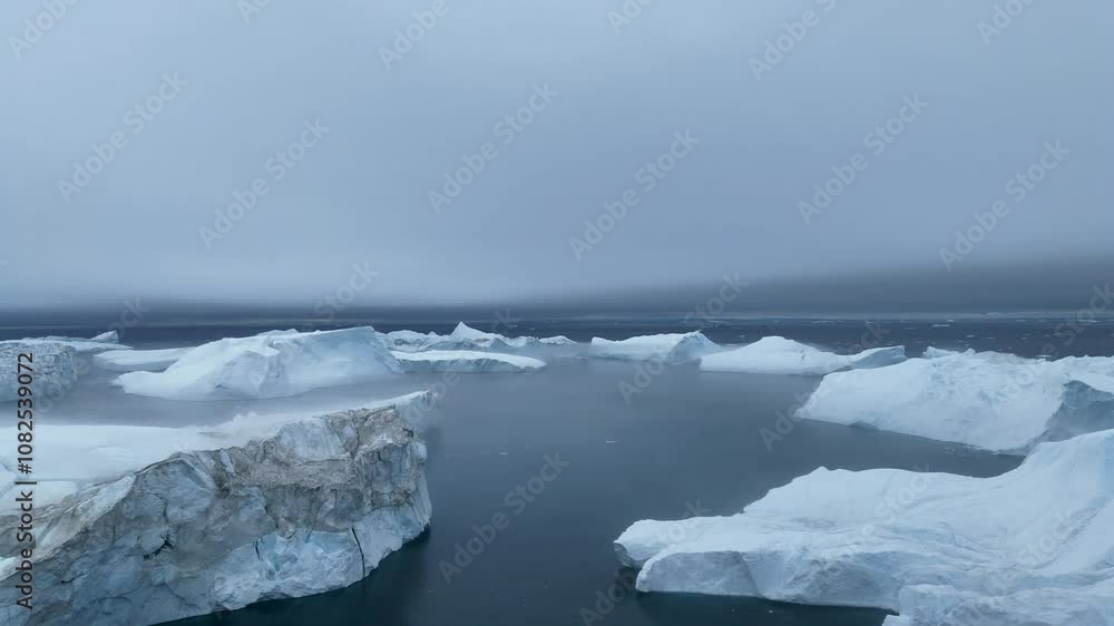 Moody view of huge icebergs floating at the horizon in the icefjord in the Disko Bay near Ilulissat in West Greenland. Epic scene in the arctic with dramatic sky Moody view of huge icebergs floating at the horizon in the icefjord in the Disko Bay near Ilulissat in West Greenland. Epic scene in the arctic with dramatic sky