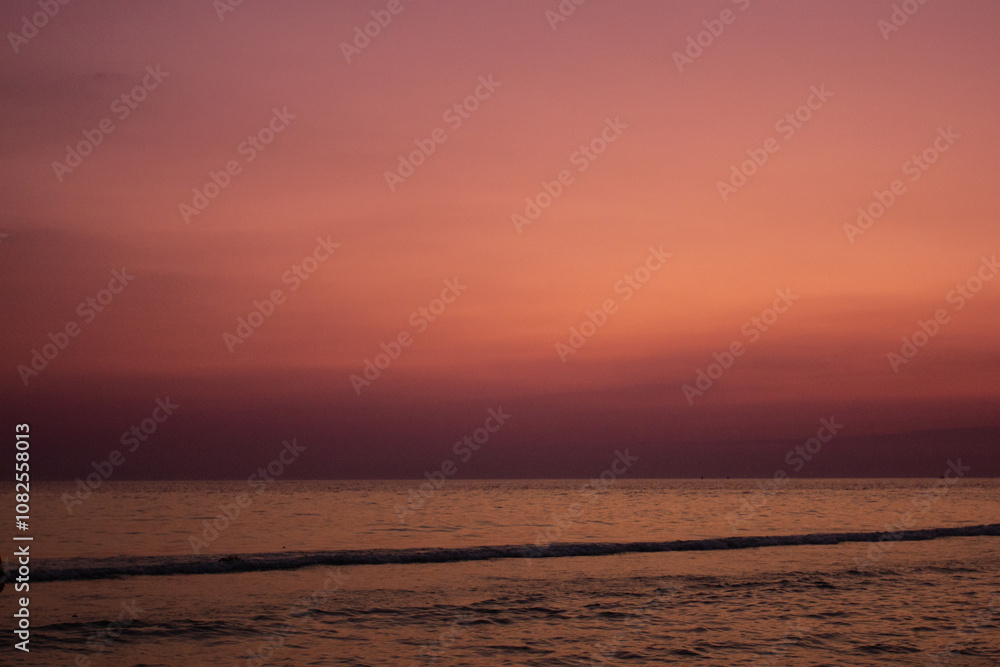 a sunset with people standing in the water and one is wearing a pink and orange sunset a sunset with people standing in the water and one is wearing a pink and orange sunset