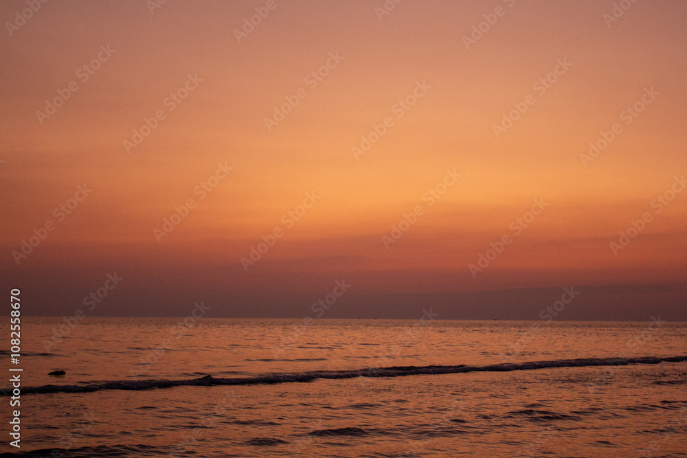 a sunset with people standing in the water and one is wearing a pink and orange sunset a sunset with people standing in the water and one is wearing a pink and orange sunset