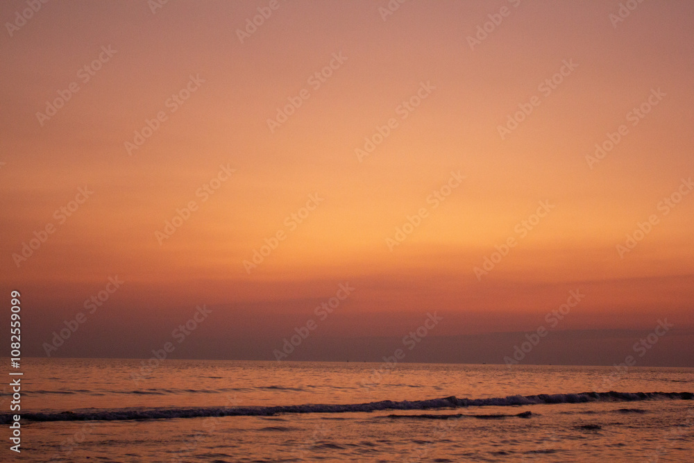 a sunset with people standing in the water and one is wearing a pink and orange sunset a sunset with people standing in the water and one is wearing a pink and orange sunset