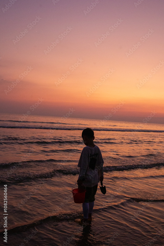 Fototapeta premium a boy is standing in the water with a bucket and bucket