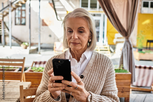 A beautiful mature woman enjoys a sunny day, connecting with someone on her phone.