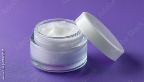 Glass cream jar with white lid on purple surface. Cosmetic product. Beauty and skin care routine.