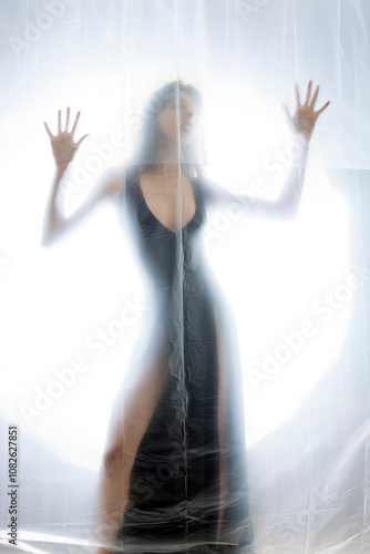 Mysterious Woman Behind Frosted Plastic Sheet in Abstract Studio Setting