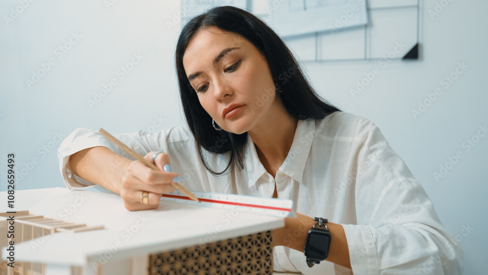 Closeup portrait image of professional young beautiful engineer architect using triangular scale measures house model with focusing at modern office. Business creative design concept. Immaculate. Closeup portrait image of professional young beautiful engineer architect using triangular scale measures house model with focusing at modern office. Business creative design concept. Immaculate.