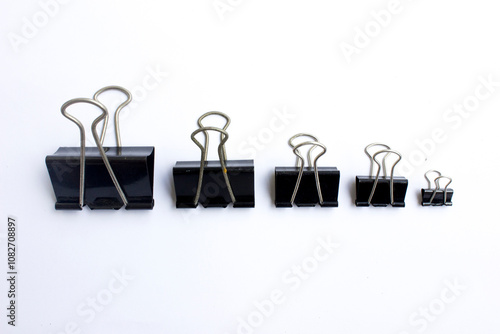 A set of black paper clip on a white background. Paper clip, a simple yet versatile office tool, holds significant importance in the business world, primarily used to bind sheets of paper together. photo