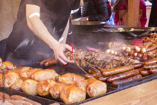 A man on the street fried on a large grill a lot of different meats and sausages during the street festival photo