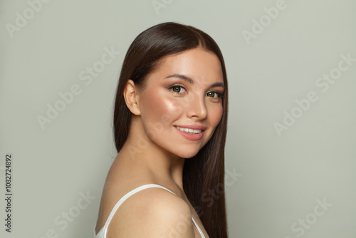 Joyful brunette woman with glowing skin, subtle makeup and a gentle smile. Young model posing, portrait