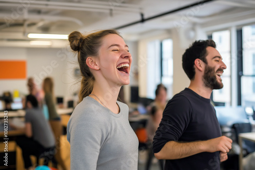 Colleagues smiling and laughing while performing light office workout routines in a shared workspace.