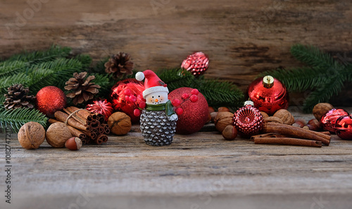 fir branches, Christmas balls, cones, cinnamon sticks, cute snowman figurine on wooden table. Christmas and new year holidays background. decorative composition for festive winter season