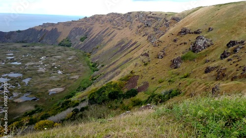 Camera pans over the rano kau volcano crater with the pacific ocean in the background on easter island