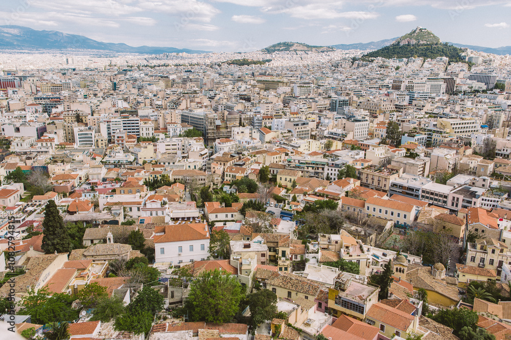 Aerial view of Athens with blue ocean and skies in the back ground. The view showcases historical buildings of the city with green domes and colourful facades. Aerial view of Athens with blue ocean and skies in the back ground. The view showcases historical buildings of the city with green domes and colourful facades.