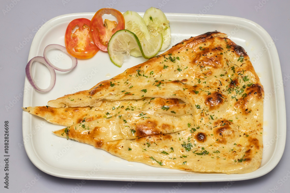 Tandoori garlic Nun, or nan with salad served in tray isolated on grey background top view of bangladesh, indian and pakistani food Tandoori garlic Nun, or nan with salad served in tray isolated on grey background top view of bangladesh, indian and pakistani food