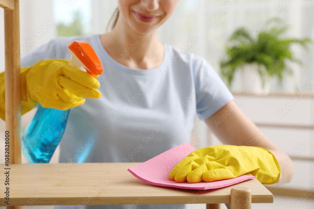 Φωτογραφία Young woman cleaning wooden shelf with rag and spray at home, closeup