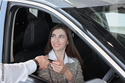 Salesman giving key to client inside new car in salon photo