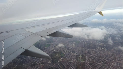 airplane departs flying over clouds brussels specifically koekelberg visible underneath from passenger's wing scene city view departure travel tourism beauty experience aerial 