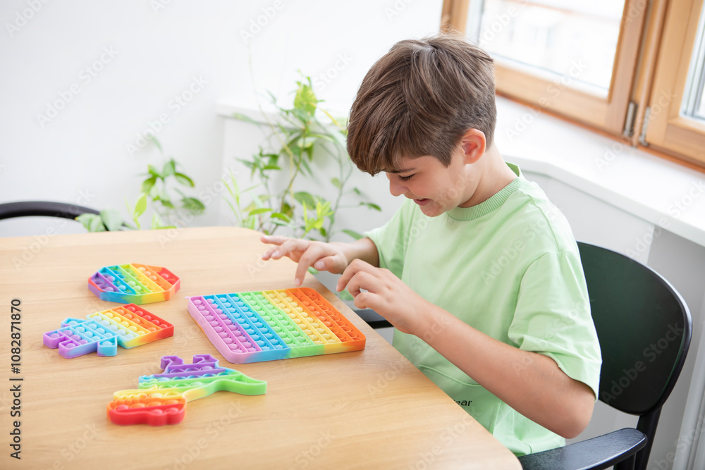 Cute happy boy plays with rainbow reusable bubble wrap popping fidget Cute happy boy plays with rainbow reusable bubble wrap popping fidget