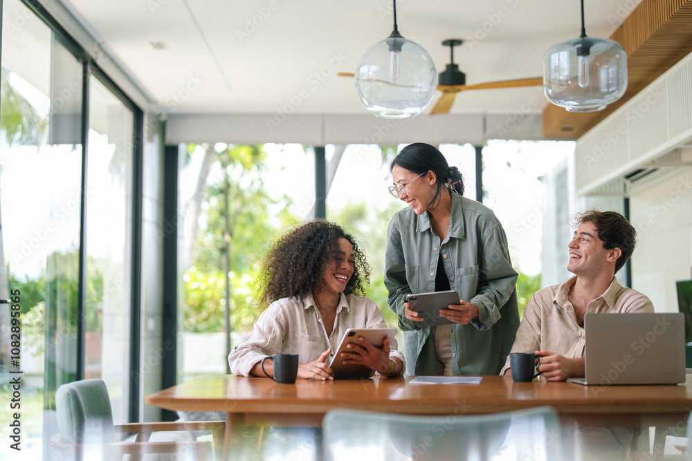 Three young adult professionals of diverse backgrounds collaborate at a modern office table, using a tablet and a laptop to enhance their discussion. Three young adult professionals of diverse backgrounds collaborate at a modern office table, using a tablet and a laptop to enhance their discussion.