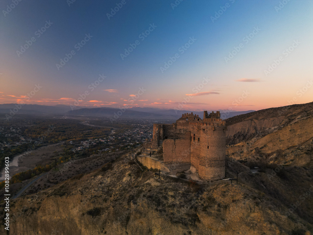 Fototapeta premium Fantasy fortress at sunset in the mountains of Georgia - Aerial Drone View,