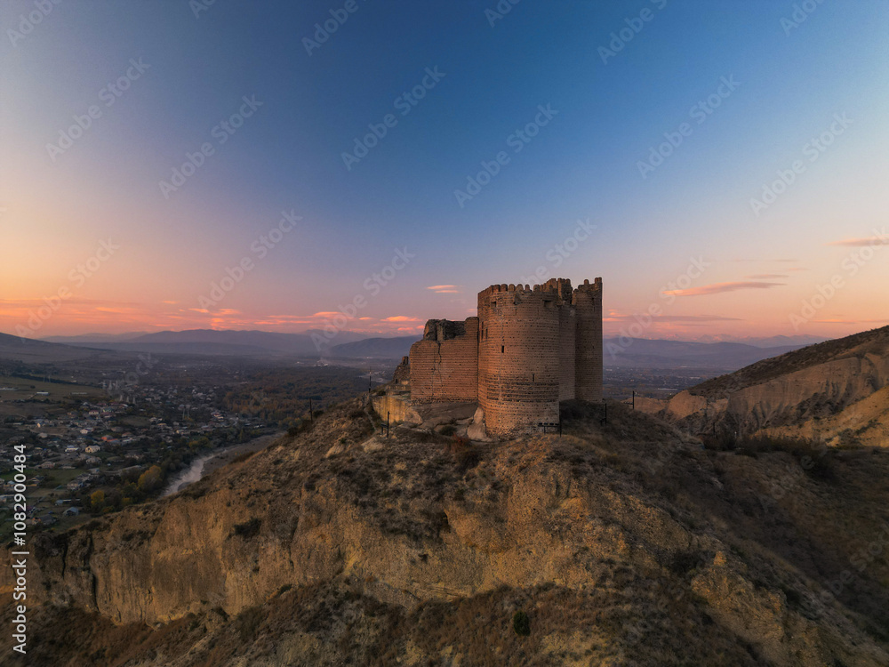 Ancient fantasy tower castle at sunset on desert mountain - drone aerial shot, Ksani, Georgia Ancient fantasy tower castle at sunset on desert mountain - drone aerial shot, Ksani, Georgia
