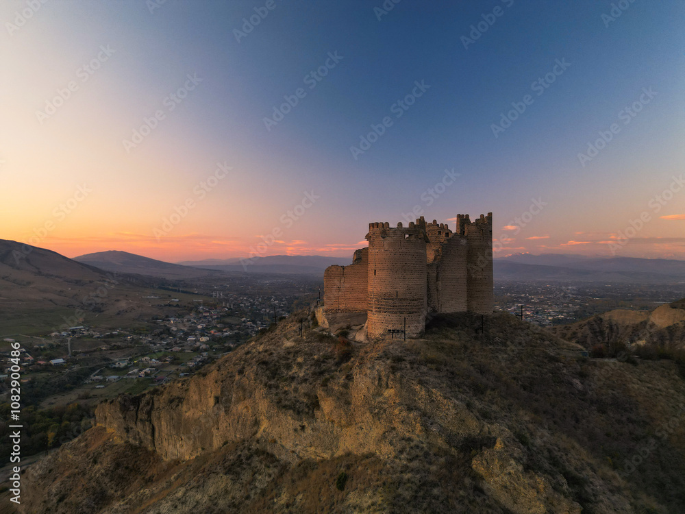 Ancient fantasy fortress on mountain at sunset - aerial drone view, georgia Ancient fantasy fortress on mountain at sunset - aerial drone view, georgia