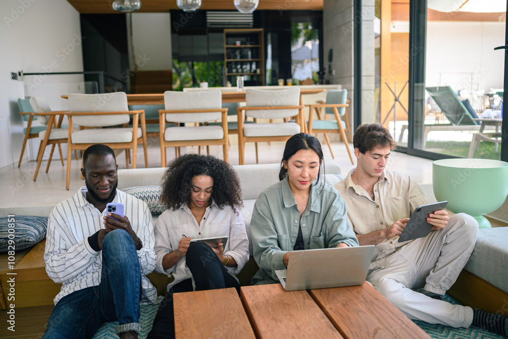A group of diverse young adults concentrate on their tasks in a stylish office lounge, each using digital devices to advance their collaborative business endeavors. A group of diverse young adults concentrate on their tasks in a stylish office lounge, each using digital devices to advance their collaborative business endeavors.