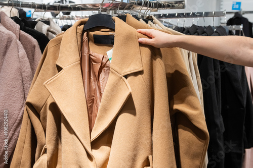 Customer Hand Picking Coat from Clothing Rack in Store photo