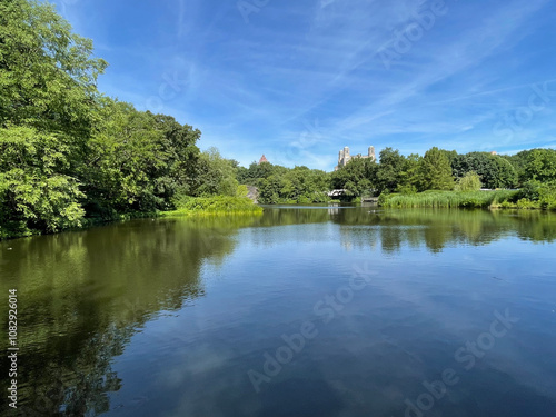 Beautiful view of the lake in Central Park, New York, with clear blue skies and city skyline in the background