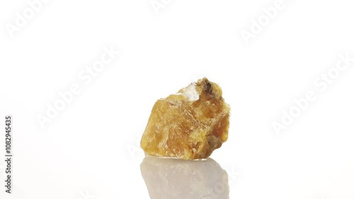 Calcite yellow mineral stone spinning in a circle on a white background