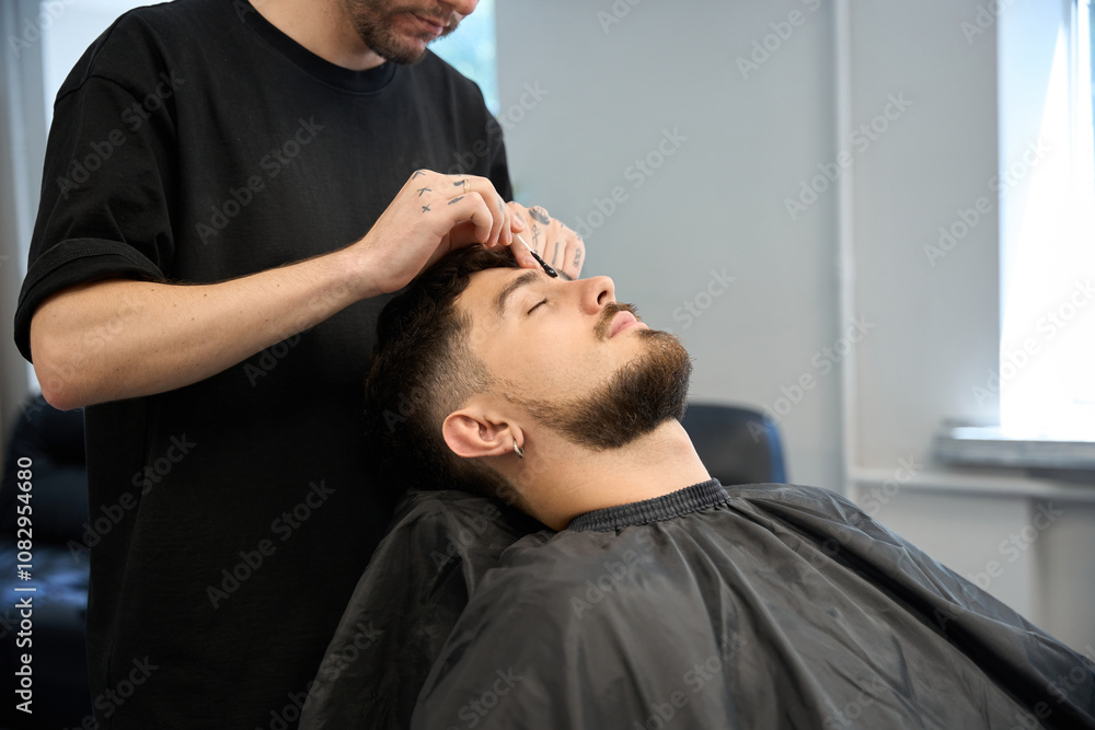 Expert groomer applies wax for hair removal between client brows Expert groomer applies wax for hair removal between client brows