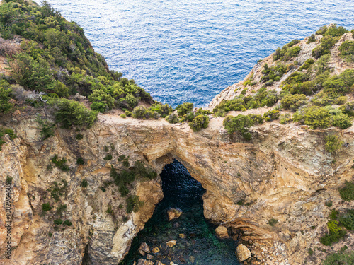 Aerial View of Natural Rock Arch and Turquoise Water Cove.. photo