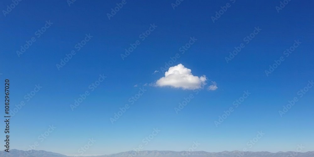 Fototapeta premium A lone white cloud drifts lazily against a deep shade of blue sky with a few distant mountains visible in the distance, mountain, gentle, serene