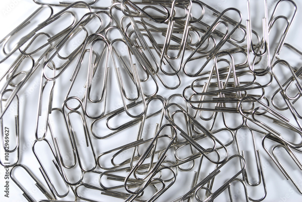 metal paper clips scattered on a white background metal paper clips scattered on a white background