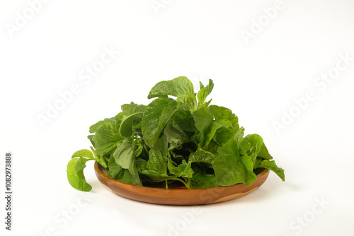 Spinach leaves in wooden bowl with isolated white background. Close up of spinach leaves. Spinach leaves are a source of vitamins and calcium. Related to the vegetarian theme photo