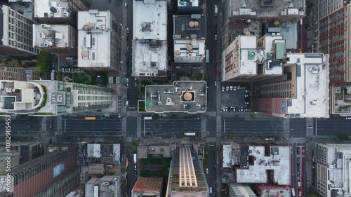 Bird's eye view of cars driving on a street with yellow cabs and pedestrians walking on the sidewalks of a crossroad in Manhattan