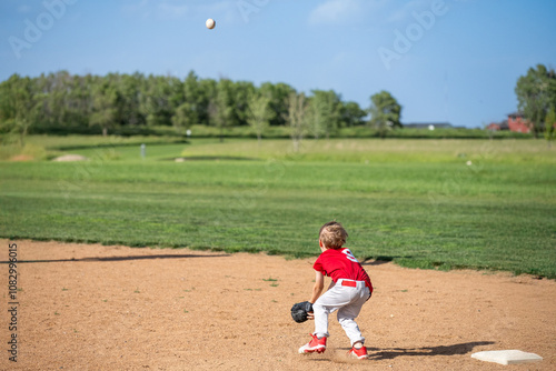 Photography Young caucasian boy catching pop fly baseball hit during a game.