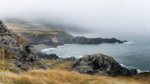 A misty rugged coastline featuring a water body in the background photo