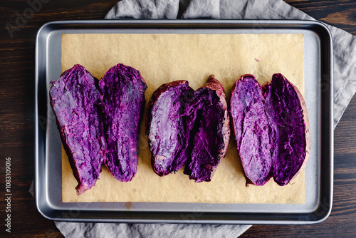 Roasted Purple Sweet Potatoes on a Sheet Pan: Sliced baked purple sweet potatoes on a parchment paper lined sheet pan