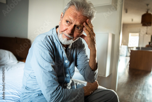 Elderly man deep in thought sitting at home photo