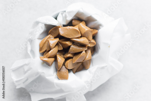 Overhead view of iloka candy on a white plate, top view of cooked condensed milk candy, Nigerian iloka candy on a white background photo