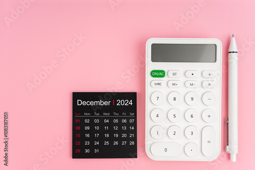 Top view of December 2024 calendar and white calculator with pen on pink background. photo