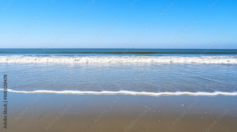 Fototapeta premium A tranquil seascape with a blue sky, calm waves, and a sandy beach.