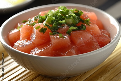 Fresh salmon poke bowl with diced salmon green onions and sesame seeds served in a white ceramic bowl with a minimal and contemporary presentation photo