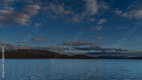 A calm blue lake. Ripples on the surface of the water. Coastal hills against the background of the evening sky and clouds. Madagascar. Mantasoa Lake photo